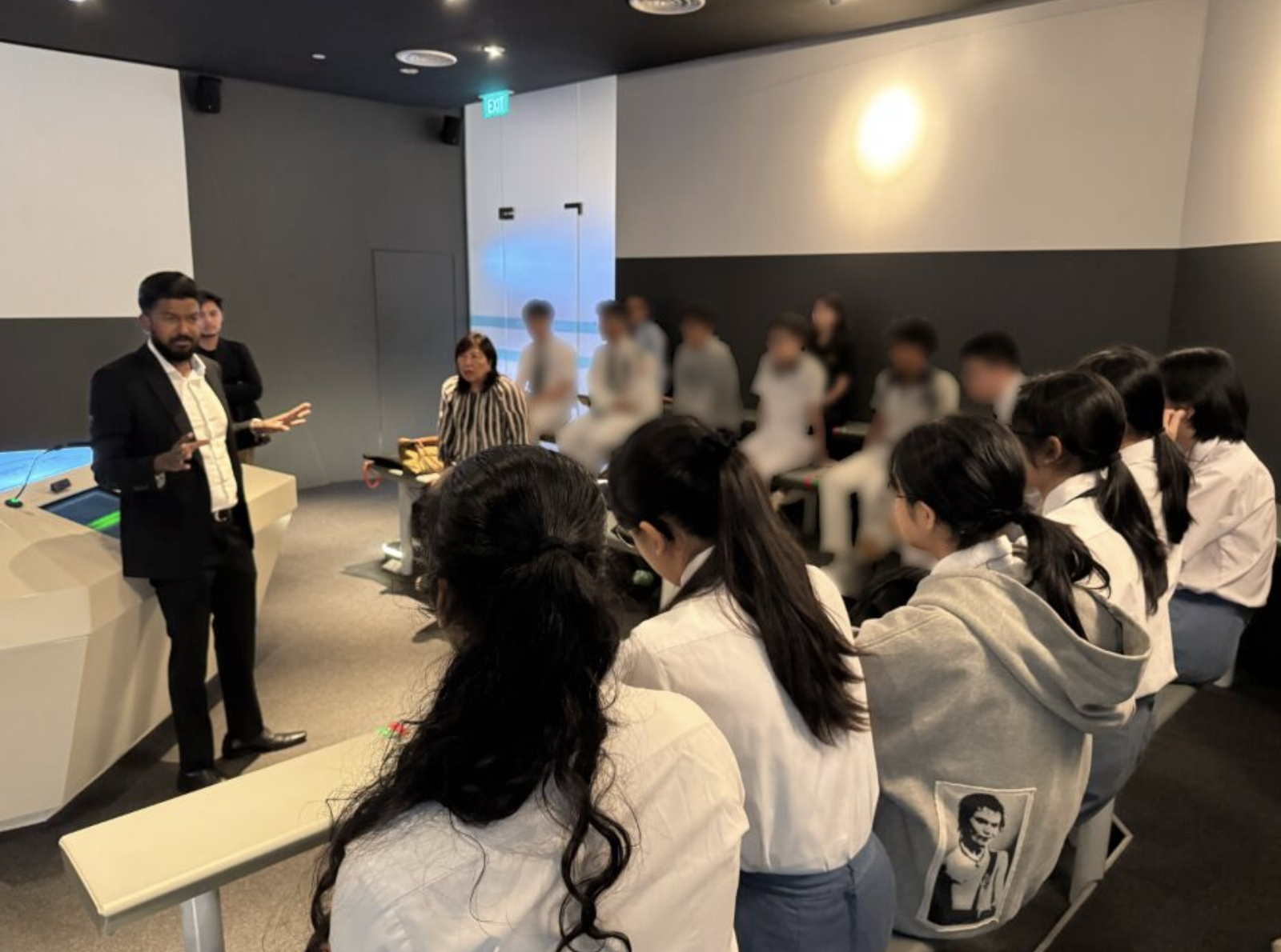 A lawyer speaking to a group of seated students in a courtroom simulation room