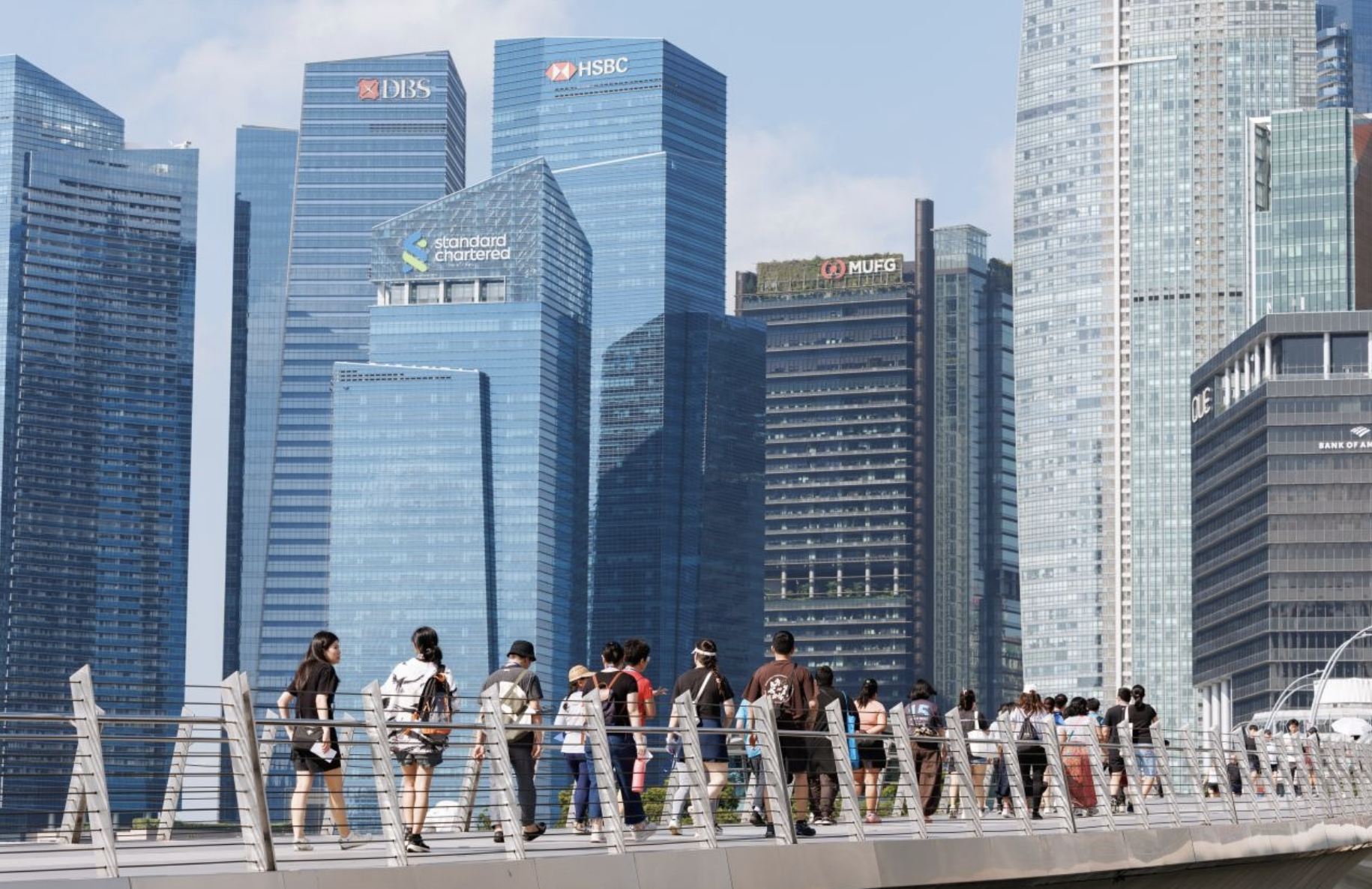 Attendees walking along the Singapore riverfront with the Marina Bay financial district skyline behind them